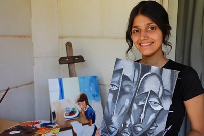Sabah holding paintings she has painted for her SOS youth leader